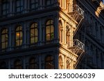 Small photo of Last sun rays on Soho loft buildings with facade ornamentation and fire escape. Soho Cast Iron Building Historic District along lower Broadway, Lower Manhattan, New York City