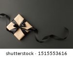 Craft gift box on a dark background, decorated with a textured bow and feathers, creating a romantic luxury atmosphere. For birthday, anniversary presents, gift post cards.