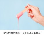 liquid pink pearl wax or sugar paste for depilation drains from the stick on blue background. The concept of depilation, waxing, sugaring smooth skin without hair, banner, copy space