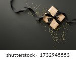 Black Friday sale flat lay with stylish gift box present and ribbon with gold star glitter on black background, flat lay, top view, copy space, xmas and holidays concept