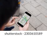 Woman with baggage in downtown city street searching location in map application online on smart phone using GPS navigating