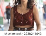 Young woman wearing a brown crochet crop top with flowers on it walking down the street