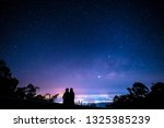 Silhouette of romantic couple watching milky way and city light at night