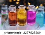 Small photo of Aqueous solutions of red, yellow and purple indicator dyes are in three glass jars.