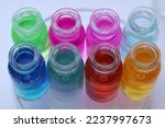 Small photo of Eight glass jars with colored aqueous solutions of various indicator dyes.