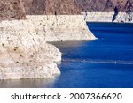 Record low water level of shrinking Lake Mead exposed white surface on rocky banks amid severe drought in American West. The lake is key reservoir along Colorado River