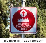 Red wildfire evacuation route sign with ahead arrow that point in the correct direction of voluntary or mandatory egress during fire emergency.