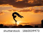 Small photo of Flexible female circus Artis keep balance and doing contortion on the rooftop against dramatic sunset and cityscape. Handstand and equilibrium concept