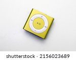 Small photo of Saint-Petersburg, Russia - May 10, 2022: Golden yellow square music player iPod Shuffle on a white background.