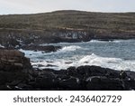 Small photo of A seascape of the ocean, cliffs, and barren shoreline under stormy conditions. The sea is rough with white caps and rolling waves. The clifftops are covered with barren grounds. The shoreline is rocky