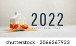 Small photo of Merry christmas and 2022 happy new year horizontal banner with small toy model house wrapped in red satin ribbon on a white background