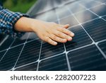 Small photo of Close up of an young engineer hand is checking an operation of sun and cleanliness of photovoltaic solar panels on a sunset. Concept:renewable energy, technology, electricity, service, green, future