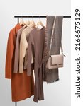 Small photo of Basic autumn women's wardrobe concept on railing in showroom. Woman collection of clothes on a rack. Autumn fashion trending concept. Railing with stylish female clothes, clothing retails concept.