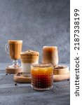 Small photo of Espresso Tonic, cold drink with espresso and tonic in glass. Ice coffee in a tall glass with cream poured over and coffee beans. Set with different types of coffee drinks on a dark table.