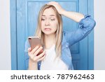Small photo of Annoyed attractive female gestures with irritation, frowns face as receives unpleasant message, clenches teeth, looks at camera, isolated over white background. Harassed or vexed woman with gadget.