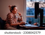 Small photo of Young woman with funny ponytail sits before computer and do online shopping in homeward