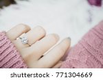Close up of an elegant engagement diamond ring on woman finger with dark pink sweater winter clothe. love and wedding concept.