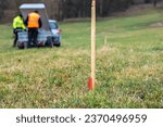 Small photo of Wood survey stake painted in red for work on construction site, workers in the background