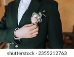 Portrait of a stylish groom, a man in a green suit with a boutonniere on his jacket. Close-up wedding photography.