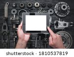 Car service worker is holding a blank screen digital tablet above spare parts background. Car spare parts order online concept.