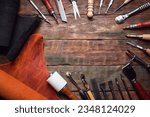 Small photo of Leather pieces and leather craft work tools on the old wooden workbench background.