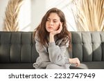 bored and sad woman sitting on couch with no mood and prop up head with hand