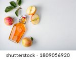 Fresh ripe apples and apple cider vinegar. Apple cider in a glass bottle and fresh apples. Light background. Top view. Copy space of your text.