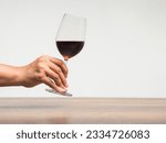 Hand holding a glass of red wine against a gray background. Space for text. Beverage and relaxation concept