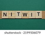Small photo of word nitwit made of small gray wooden letters on a green paper background