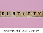 Small photo of word subtlety from small gray wooden letters lies on a pink background