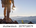 Hikers with backpacks holding binoculars standing on top of the rock mountain at sunset background