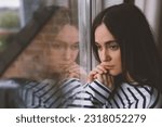 Small photo of Very sad lonely girl. Depression and worried woman at home. Upset lady looking at the window.