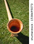 Small photo of Close up view of a wooden Alpine horn (also Alphorn or Alpenhorn), a straight several-meter-long wooden natural horn of conical bore, with a wooden cup-shaped mouthpiece. Portrait format.