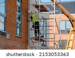 Small photo of Construction workers using aluminium mobile scaffold tower and safety harness to work at height. Working at height safety regulation