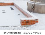 Concrete foundation for a new house in the wintertime under snow. Construction works on stop due to snow