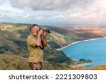 Bearded Man reaching the destination and on the top of mountain at sunset on autumn day and taking photos of amazing landscape. Travel Lifestyle concept. The national park Lake District in England