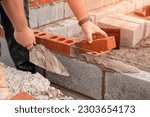 Bricklayer laying brick on cement mix on construction site close-up. Reduce the housing crisis by building more affordable houses concept