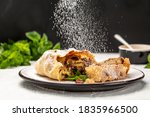 Apple strudel cake with cinnamon, mint and raisins on light background, with sieve sprinkling sugar powder from above. austrian germany food.
