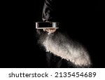 Small photo of the chef sprinkles flour through a sieve, Powdery flour flying into air. chef hands with flour in a freeze motion of a cloud of flour midair.