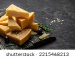 Small photo of Parmesan cheese on a wooden board, Hard cheese on a dark background. banner, menu, recipe place for text, top view.