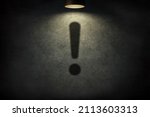 Small photo of Exclamation mark design with spotlight on textured black wall background