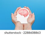 Mental health and problems with memory. Hands holding a paper with a human head and brain in the palm.