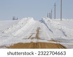 Gravel road lined with deep snow drifts.