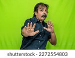 Small photo of The well-dressed Indian man, wearing a black shirt, suddenly flailed his hands and contorted his face in a terrified expression while standing against a green screen background