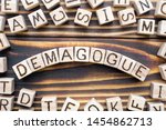 Small photo of demagogue wooden cubes with letters, populist exciting the emotions concept, around the cubes random letters, top view on wooden background