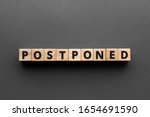 Small photo of Postponed - words from wooden blocks with letters, postponed concept, top view gray background