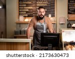 Small photo of Male barista at counter using cashbox computer in cafe store. Indian Waiter in apron working in coffee shop.small business, people and service concept
