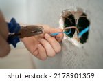 man works with electrical wires using tools, fixing socket at home, male household work with electricity, pliers and wire cutters in man's hands, electrician working with wire