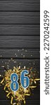 Small photo of Number 86 blue celebration candle and gold confetti on dark wooden background. 86th birthday card. Anniversary and birthday concept. Vertical banner. Copy space