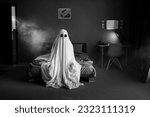 Ghost in a white sheet sits on...